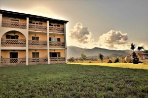 a building with a grass field in front of it at Elpida Hotel in Alikanas