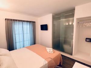 um quarto com uma cama e uma cabina de duche em vidro em bhc Boutique Hostal Cala Millor em Cala Millor