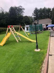 a playground with a yellow slide on the grass at Meadow House in County Donegal in Donegal