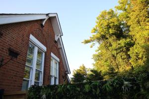a brick house with a window and a hedge at The Old Schoolhouse in Whitstable