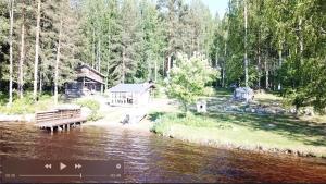 a cabin next to a river with a bench at Könölä in Outokumpu