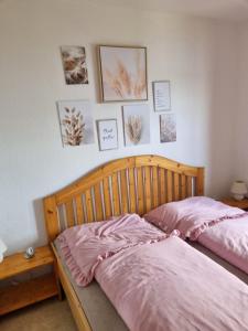 a bed with pink sheets and pictures on the wall at ELBBLICK in Storkau
