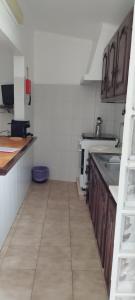 uma cozinha com armários de madeira e uma bancada em Apartamento Rosa em Porto Covo