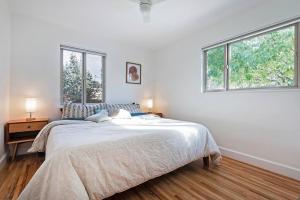 a white bedroom with a bed and two windows at Mid-century, modern oasis, fully stocked in Murray