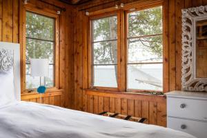 a bedroom with a bed in a wooden room with windows at Lee Point Classic Cabins on West Bay with Hot Tub in Suttons Bay