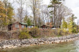 a house with a stone wall next to a river at Lee Point Classic Cabins on West Bay with Hot Tub in Suttons Bay
