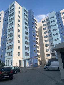 a large building with cars parked in a parking lot at Blue Joy Bukovina Aparthotel in Suceava