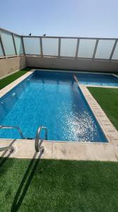 ein großer Pool in einem Gebäude mit grünem Gras in der Unterkunft قصور الشرق للاجنحة الفندقية Qosor Al Sharq in Dschidda