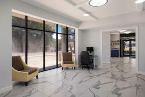 an office lobby with chairs and a desk and windows at Suburban Studios in Hinesville