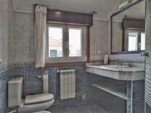 a bathroom with a toilet and a sink and a window at Desconectaengalicia Ático La Lanzada in A Lanzada