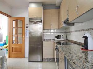 a kitchen with a stainless steel refrigerator and wooden cabinets at Desconectaengalicia Ático La Lanzada in A Lanzada