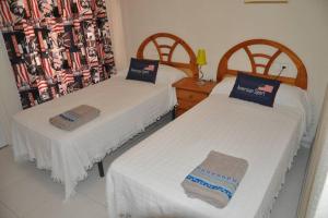 deux lits dans une chambre avec des draps blancs dans l'établissement Duplex junto al Mar con Jardin y Piscina, à Puerto de Mazarrón