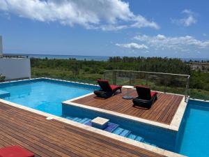 a swimming pool with two chairs on a wooden deck at Grand Fifty Suites in Playa del Carmen