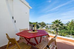 - une table rouge avec 2 chaises et des bouteilles de vin sur le balcon dans l'établissement BmyGuest - Quinta do Lago Terrace Apartment II, à Quinta do Lago