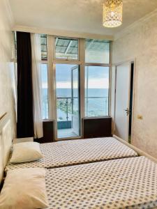 a bedroom with two beds and a large window at Batumi seaside Magnolia in Batumi