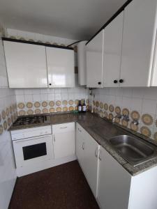 een kleine keuken met witte kasten en een spoelbak bij Playa de Aro in Platja  d'Aro +10 foto's