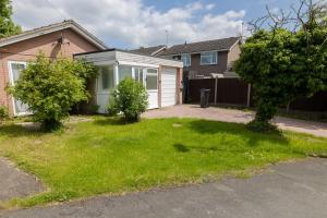 a house with a grass yard in front of it at Lindrick Villa- 3BD Bunglow , Free parking- Long stays in Leicester