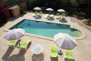 a swimming pool with lawn chairs and umbrellas at Casa Canavial in Lagos