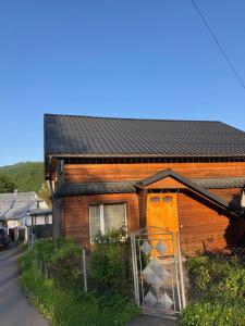 une maison en bois avec une porte ouverte dans une rue dans l'établissement Садиба Криниченька, à Yaremtche