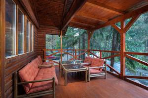 un porche de una cabaña con 2 sillas y una mesa en TATRYSTAY Chalet Kristina, en Demänovská Dolina