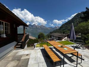 a patio with a wooden table and an umbrella at Chalet im Gus - Flumserberge & Walensee in Oberterzen
