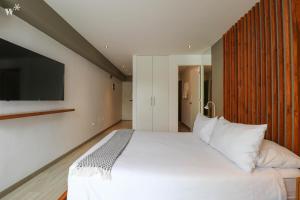 a bedroom with a large white bed with a flat screen tv at Primera Parada By Wynwood House in Lima +151 photos