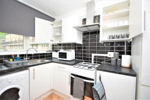 eine Küche mit weißen Geräten und schwarzen Fliesen in der Unterkunft Lovely 2 bed Flat in S/E London in Abbey Wood