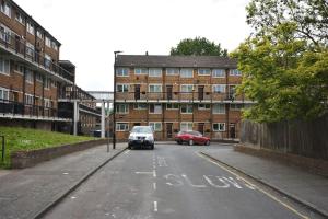 ein Auto, das vor einem Gebäude eine Straße hinunterfährt in der Unterkunft Lovely 2 bed Flat in S/E London in Abbey Wood