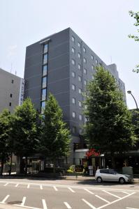 samochód zaparkowany przed dużym budynkiem w obiekcie Hotel Route-Inn Tokyo Asagaya w Tokio