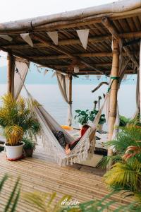 a person laying in a hammock on a deck at Hometown Riverview - โฮมทาวน์ ริเวอร์วิว in Si Sawat