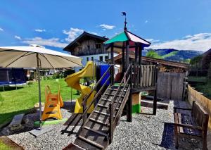 einen Spielplatz mit Rutsche und Sonnenschirm in der Unterkunft Apartment Bergblick, 3 Schlafzimmer, 2 Badezimmer in Kirchberg in Tirol
