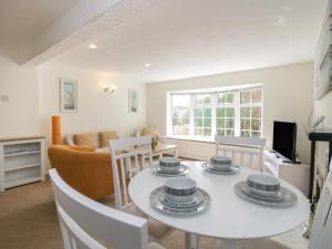uma sala de jantar e sala de estar com uma mesa branca e cadeiras em The Cottage em Barrow in Furness