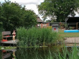 una mujer parada en un muelle junto a un estanque en Landtraum im Traumland Mecklenburg en Warin