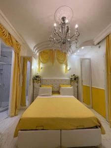 Un dormitorio con una gran cama amarilla con una lámpara de araña en Chambre de luxe 95 Grise, en Deuil-la-Barre