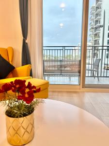 Charming Yas Island Stay with Balcony في أبوظبي: غرفة معيشة مع مزهرية مع الزهور على طاولة