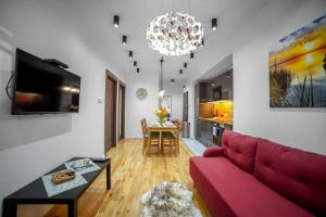 a living room with a red couch and a table at Nowoczesny dwupokojowy Apartament Bridget z parkingiem in Ełk