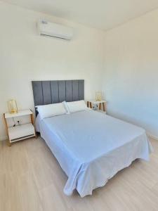 1 dormitorio blanco con 1 cama grande y 2 mesas en Hermoso departamento con vistas al verde y pileta! en Pilar