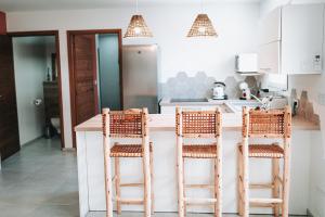 a kitchen with a counter with three stools at Maloé Lodge T2 (2 min à pieds plage et surf) in Sainte-Anne