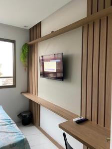 een slaapkamer met een flatscreen-tv aan de muur bij Estúdio com Decoração Charmosa e Piscina compart in Salvador
