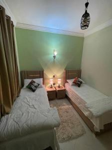 2 Einzelbetten in einem Zimmer mit 2 Lampen in der Unterkunft MAGHREB IMMO in Meknès