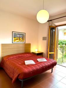 1 dormitorio con 1 cama con colcha roja en Appartamenti Portiglioni-Cipressi, en Puntone di Scarlino
