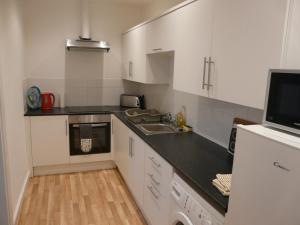 una piccola cucina con armadi bianchi e lavandino di The Torrs Apartments New Mills a New Mills