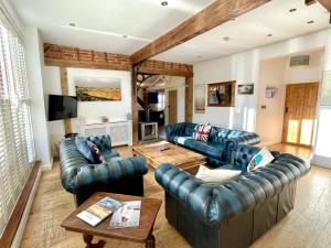a living room with blue leather couches and a table at The Cart Lodge at Lee Wick Farm Cottages & Glamping in Saint Osyth