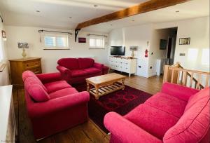 a living room with red couches and a tv at The Cart Lodge at Lee Wick Farm Cottages & Glamping in Saint Osyth