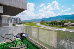 a balcony with a table and chairs and a river at Happy apartment Ilidža in Sarajevo