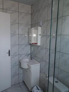 a white bathroom with a sink and a toilet at Pousada dos Reis in Barra de Ibiraquera