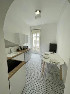 a white kitchen with a table and a table and chairs at Appartemment Nimes Arènes in Nîmes