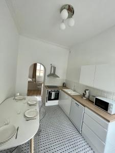 uma cozinha branca com uma mesa e um lavatório em Appartemment Nimes Arènes em Nîmes