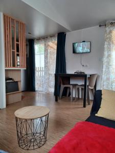a living room with a table and a couch at Le Cosy, mobil-home 4-6 personnes au camping les Sables du Midi à Valras-Plage in Valras-Plage