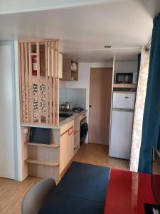 a small kitchen with a counter and a refrigerator at Le Cosy, mobil-home 4-6 personnes au camping les Sables du Midi à Valras-Plage in Valras-Plage +6 photos